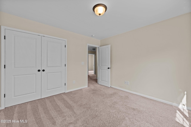 unfurnished bedroom featuring carpet, baseboards, and a closet