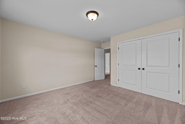 unfurnished bedroom featuring carpet, a closet, and baseboards