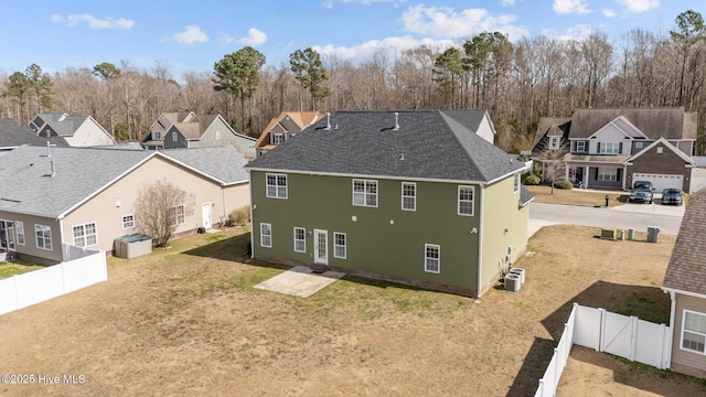 back of house with a shingled roof, a residential view, a fenced backyard, and a yard