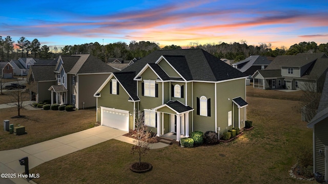 traditional-style home featuring concrete driveway, an attached garage, and a front lawn