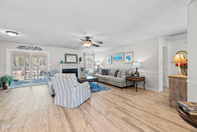 living area with a healthy amount of sunlight, a fireplace, visible vents, and wood finished floors