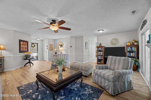 living area with light wood-style floors, visible vents, and a textured ceiling