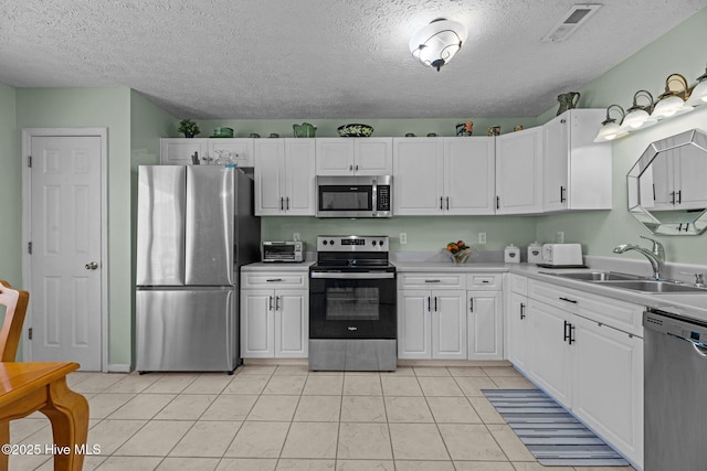 kitchen featuring stainless steel appliances, a sink, visible vents, and white cabinets