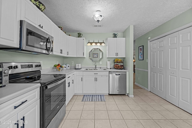 kitchen featuring appliances with stainless steel finishes, light countertops, visible vents, and a sink