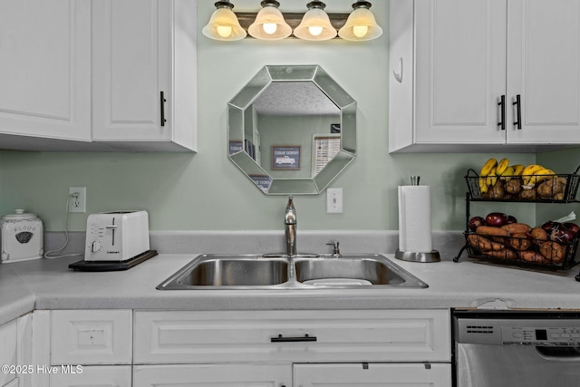 kitchen with light countertops, stainless steel dishwasher, a sink, and white cabinets