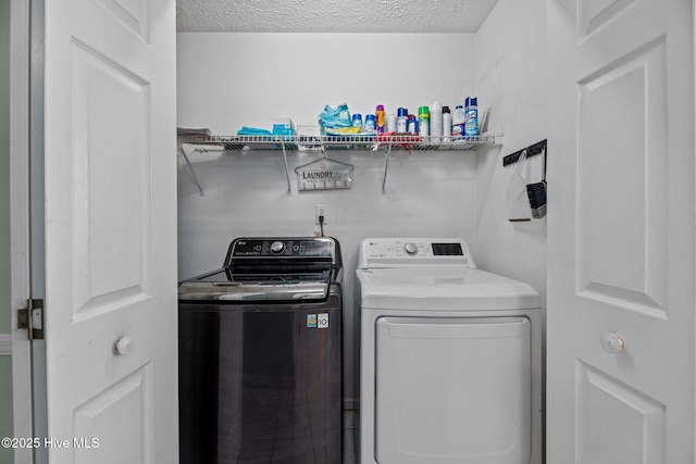 washroom featuring laundry area, washer and clothes dryer, and a textured ceiling