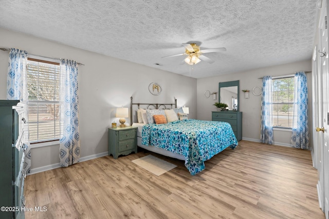 bedroom with light wood-type flooring, baseboards, and a textured ceiling