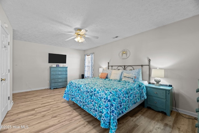 bedroom with a ceiling fan, a textured ceiling, baseboards, and wood finished floors