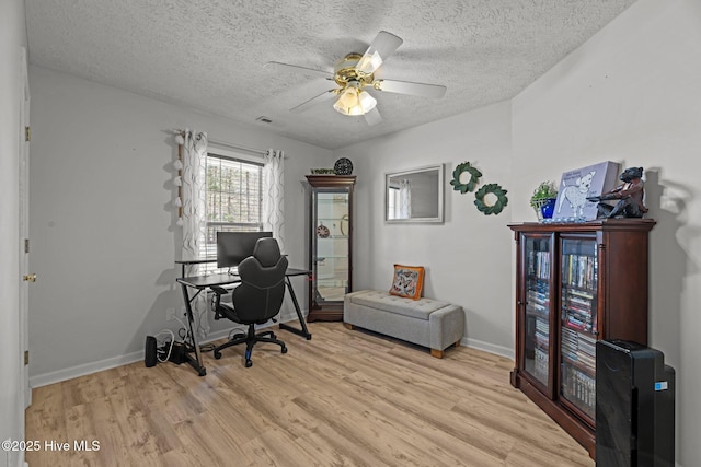 office with visible vents, a ceiling fan, a textured ceiling, light wood-type flooring, and baseboards