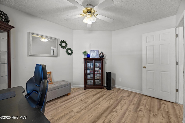 office with a ceiling fan, baseboards, a textured ceiling, and light wood finished floors