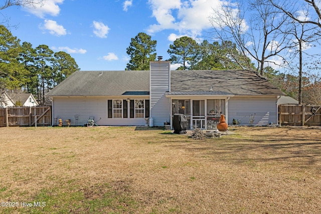 rear view of property with a sunroom, a chimney, fence, and a yard