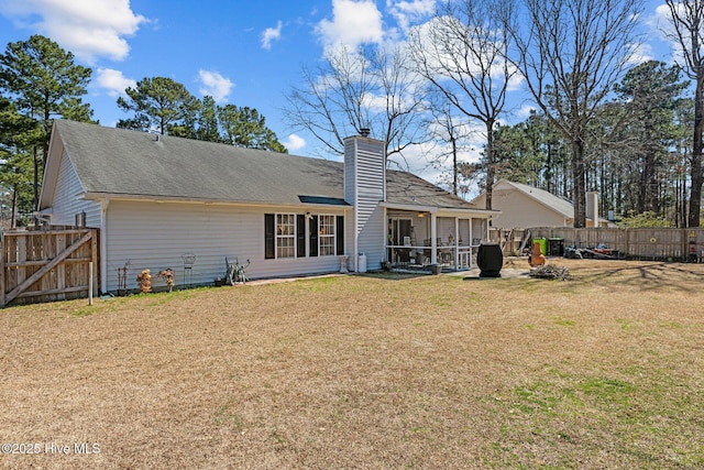 back of house with a sunroom, a yard, a chimney, and fence