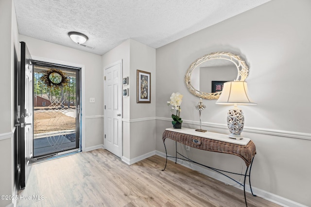 entryway with visible vents, a textured ceiling, baseboards, and wood finished floors