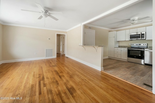 interior space with ceiling fan, ornamental molding, and light wood-type flooring