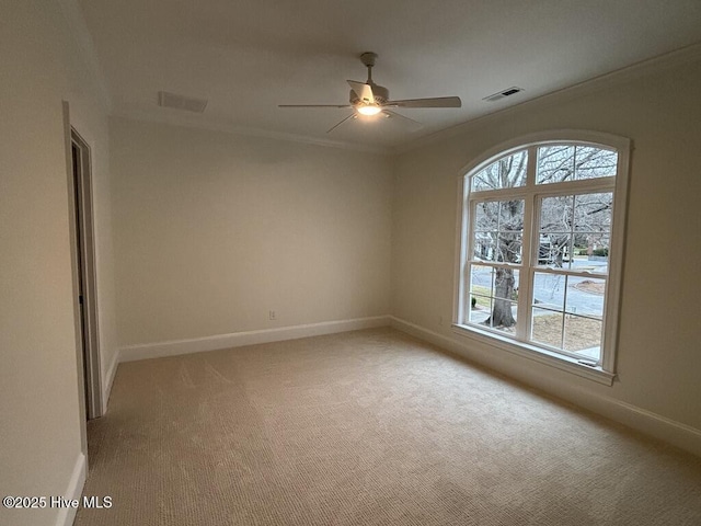 empty room featuring light carpet, baseboards, visible vents, and crown molding