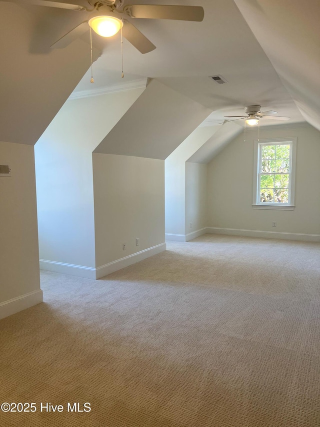 bonus room with lofted ceiling, visible vents, a ceiling fan, light carpet, and baseboards