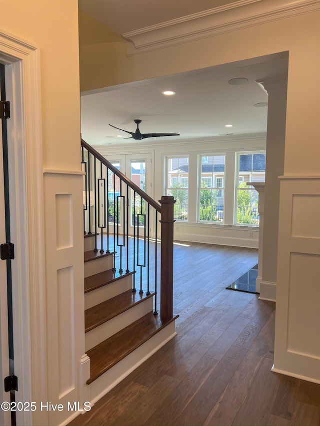 stairs with recessed lighting, wood finished floors, a ceiling fan, baseboards, and ornamental molding