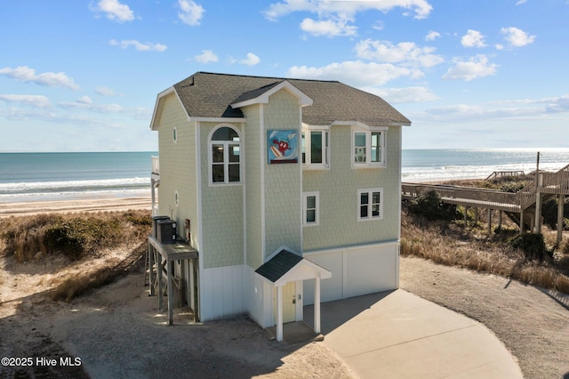 view of property exterior with a garage, a water view, and a beach view