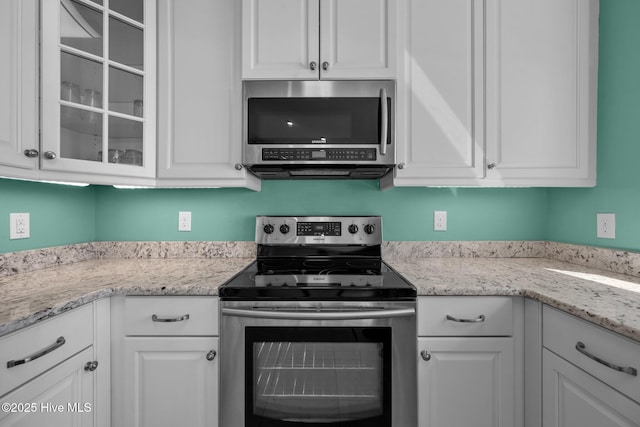 kitchen with stainless steel appliances, white cabinets, and light stone counters