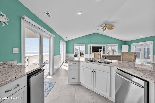 kitchen with lofted ceiling, sink, light stone counters, dishwasher, and white cabinets