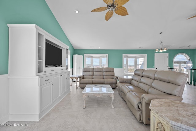 tiled living room with ceiling fan with notable chandelier and vaulted ceiling