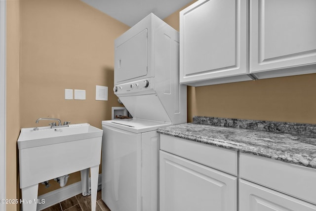 laundry room with sink, cabinets, and stacked washer and clothes dryer