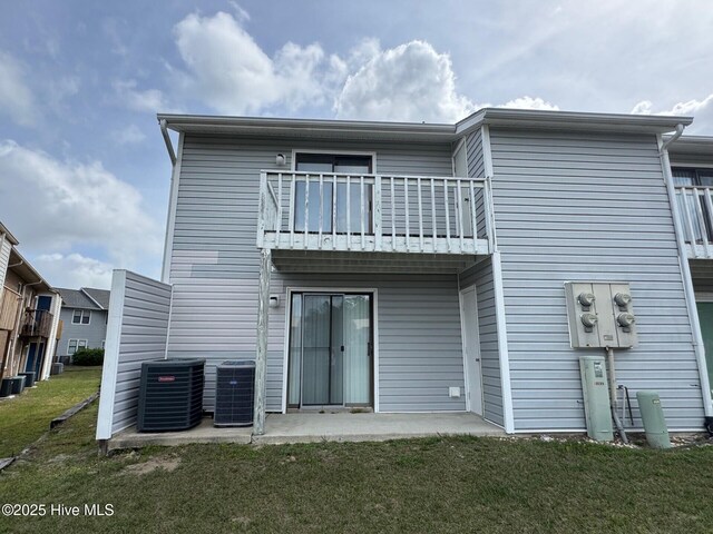 back of property featuring cooling unit, a balcony, a patio, and a lawn