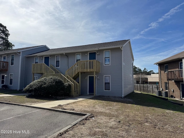 rear view of property with stairs, a yard, and fence