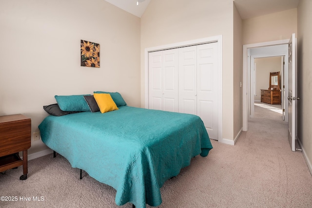 bedroom featuring lofted ceiling, a closet, light carpet, and baseboards