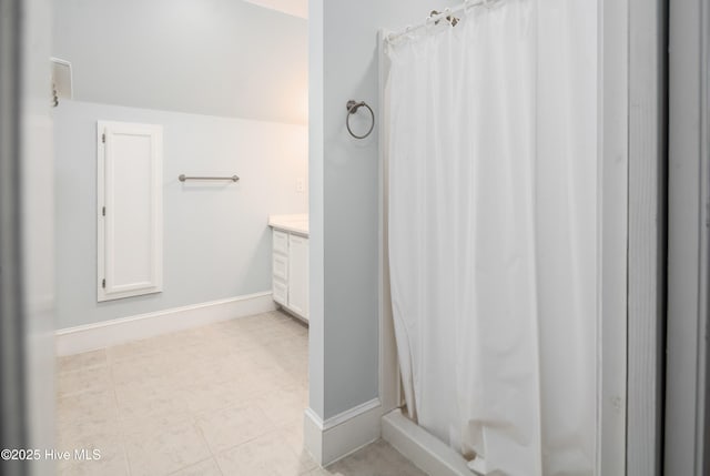 bathroom with tile patterned floors, baseboards, curtained shower, and vanity