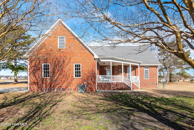 view of front facade featuring a front yard, covered porch, and brick siding