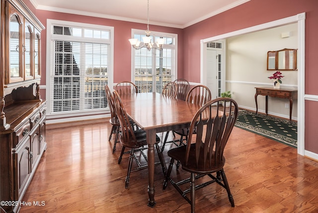 dining space with ornamental molding, a notable chandelier, light wood-style floors, and baseboards