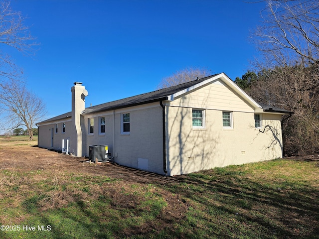 view of side of home with central AC unit and a yard