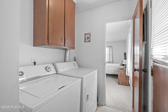 washroom featuring ornamental molding, washer and dryer, and cabinet space