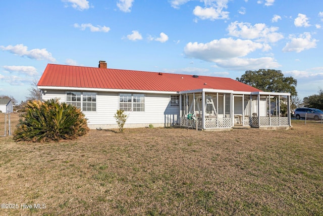 back of house with a yard, a sunroom, metal roof, and a chimney