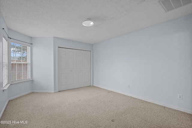 unfurnished bedroom with a textured ceiling, a closet, and light colored carpet