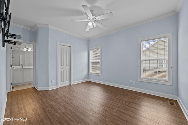 unfurnished bedroom featuring hardwood / wood-style flooring, ornamental molding, multiple windows, and a closet