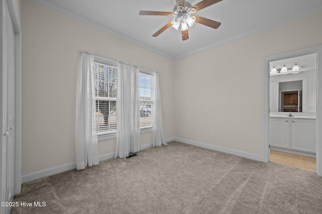 unfurnished bedroom featuring sink, crown molding, ceiling fan, ensuite bathroom, and light colored carpet