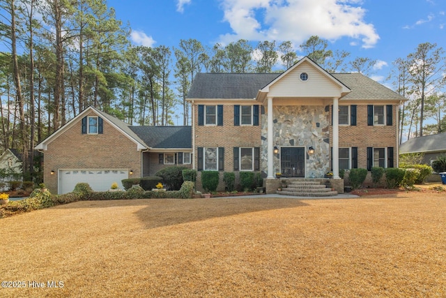 greek revival house featuring brick siding, stone siding, and a garage