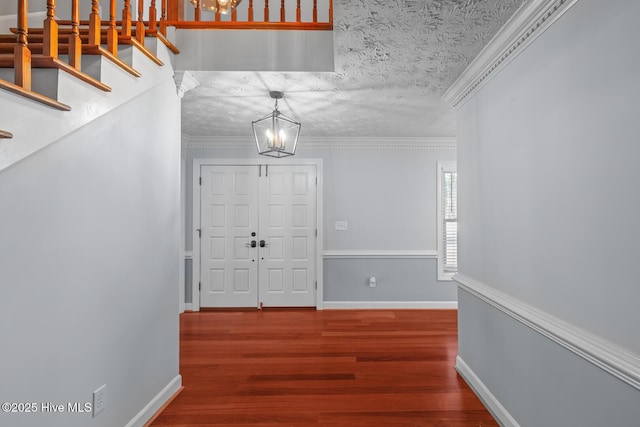 foyer featuring an inviting chandelier, hardwood / wood-style flooring, a textured ceiling, and ornamental molding