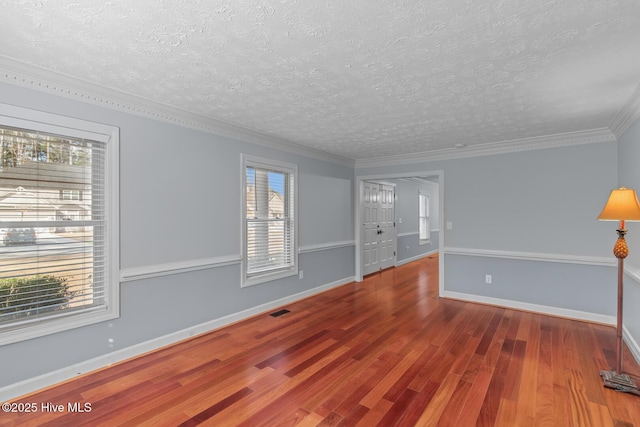 spare room with crown molding, a textured ceiling, a wealth of natural light, and hardwood / wood-style floors