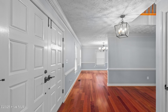 hall with a textured ceiling, ornamental molding, hardwood / wood-style floors, and a chandelier