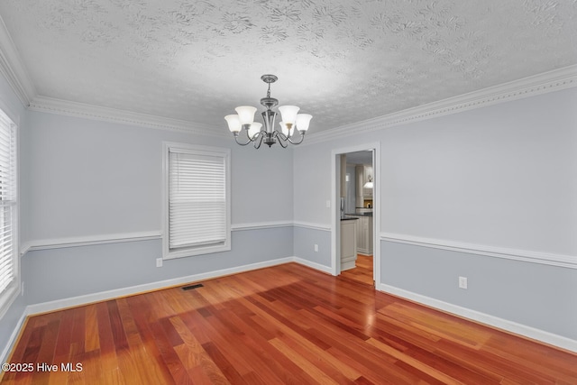 spare room featuring hardwood / wood-style floors, an inviting chandelier, crown molding, and a textured ceiling