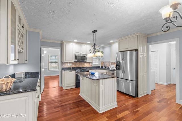 kitchen with stainless steel appliances, pendant lighting, hardwood / wood-style floors, a kitchen island, and white cabinetry