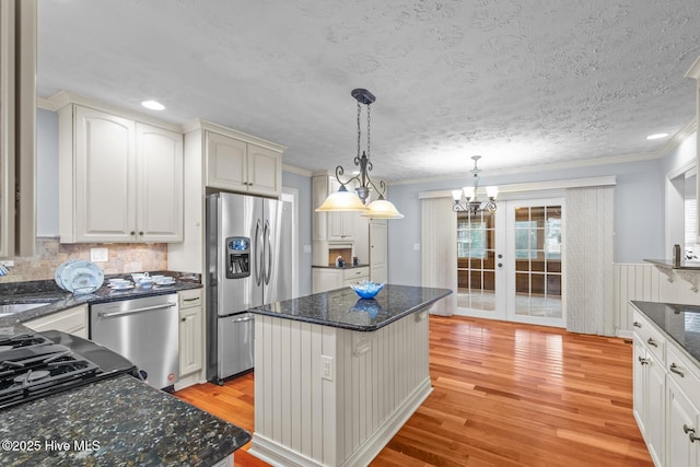 kitchen with appliances with stainless steel finishes, a center island, white cabinetry, pendant lighting, and light wood-type flooring