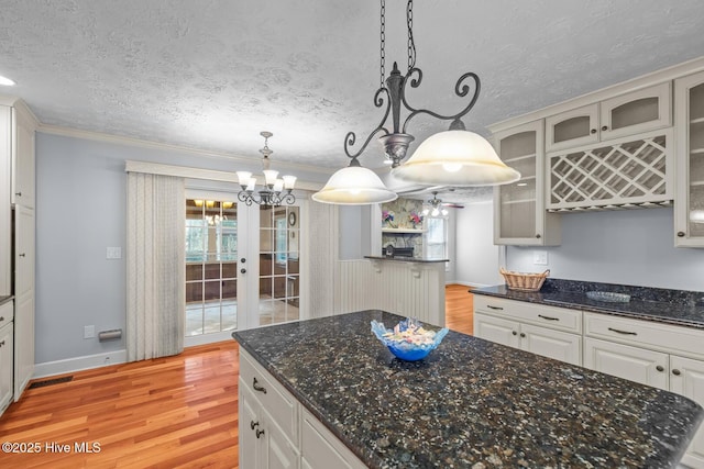 kitchen featuring white cabinetry, light hardwood / wood-style flooring, hanging light fixtures, and a center island