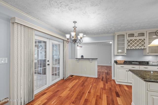 kitchen featuring light wood-type flooring, pendant lighting, white cabinetry, and a textured ceiling