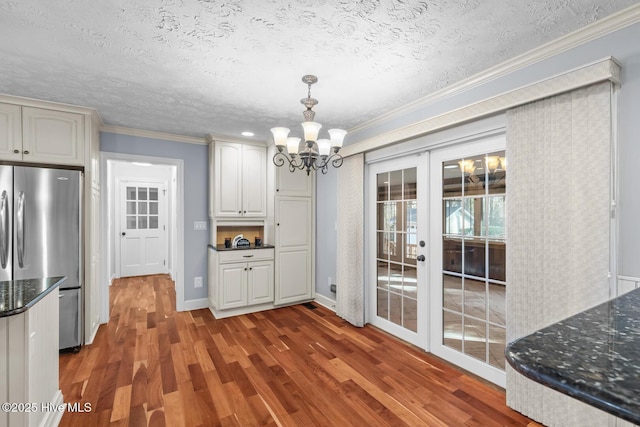 interior space featuring french doors, a textured ceiling, a chandelier, ornamental molding, and dark hardwood / wood-style floors