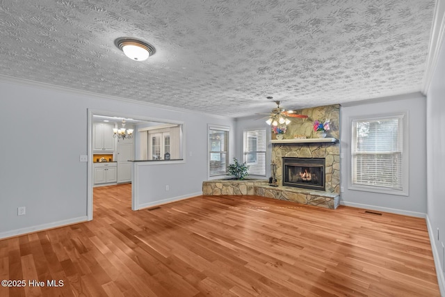 unfurnished living room featuring ornamental molding, a stone fireplace, and light hardwood / wood-style floors