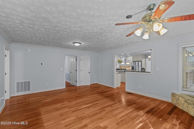 unfurnished living room featuring hardwood / wood-style floors, a textured ceiling, ceiling fan, and ornamental molding